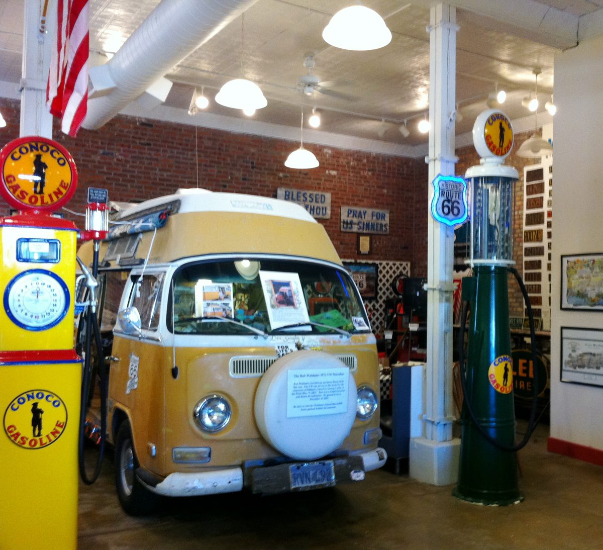 Bob Waldmire's Volkswagen van, painted yellow and white, on display indoors beside vintage gas pumps